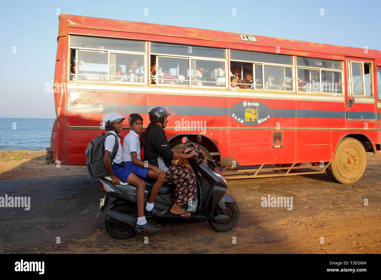 Sri Lankan mother and school going kids riding on a scooty at Chilaw, Srilanka. Stock Photo