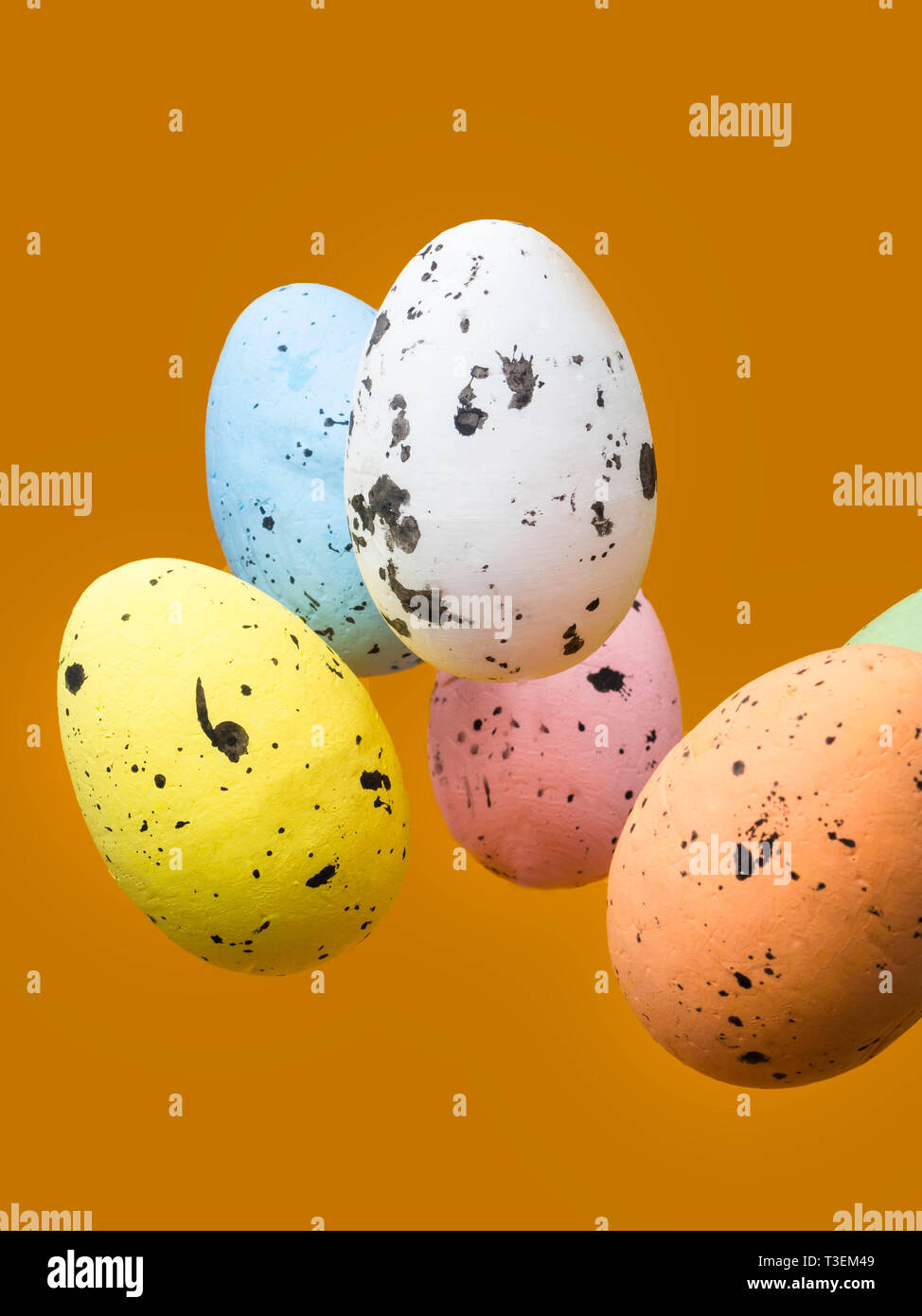 Easter scene with colored eggs flying on orange background Stock Photo