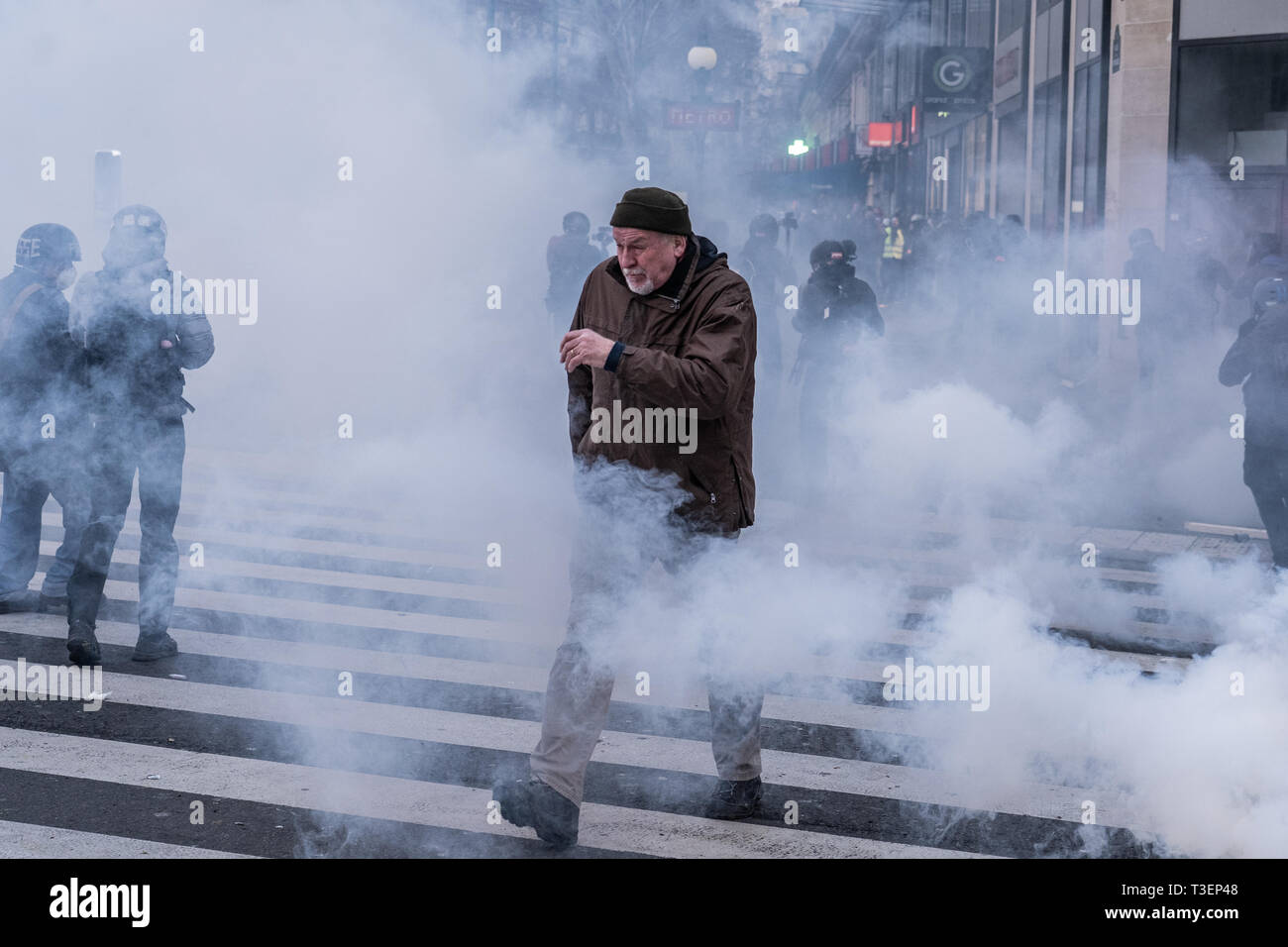 An old men walking through tear gaz during a 'Yellow Vests' demonstration on the Republic square in Paris on February 2, 2019 Stock Photo