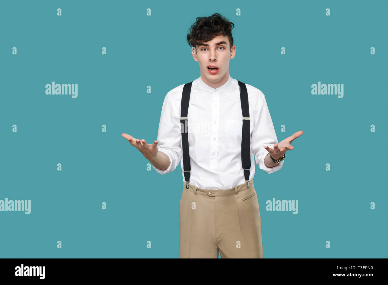 What do you want? man asking and looking at camera. Portrait of handsome hipster curly young businessman in classic casual white shirt and suspender s Stock Photo