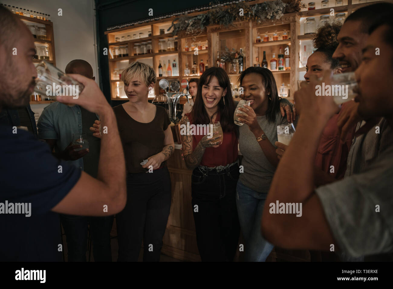 Friends drinking and talking together in a bar at night Stock Photo