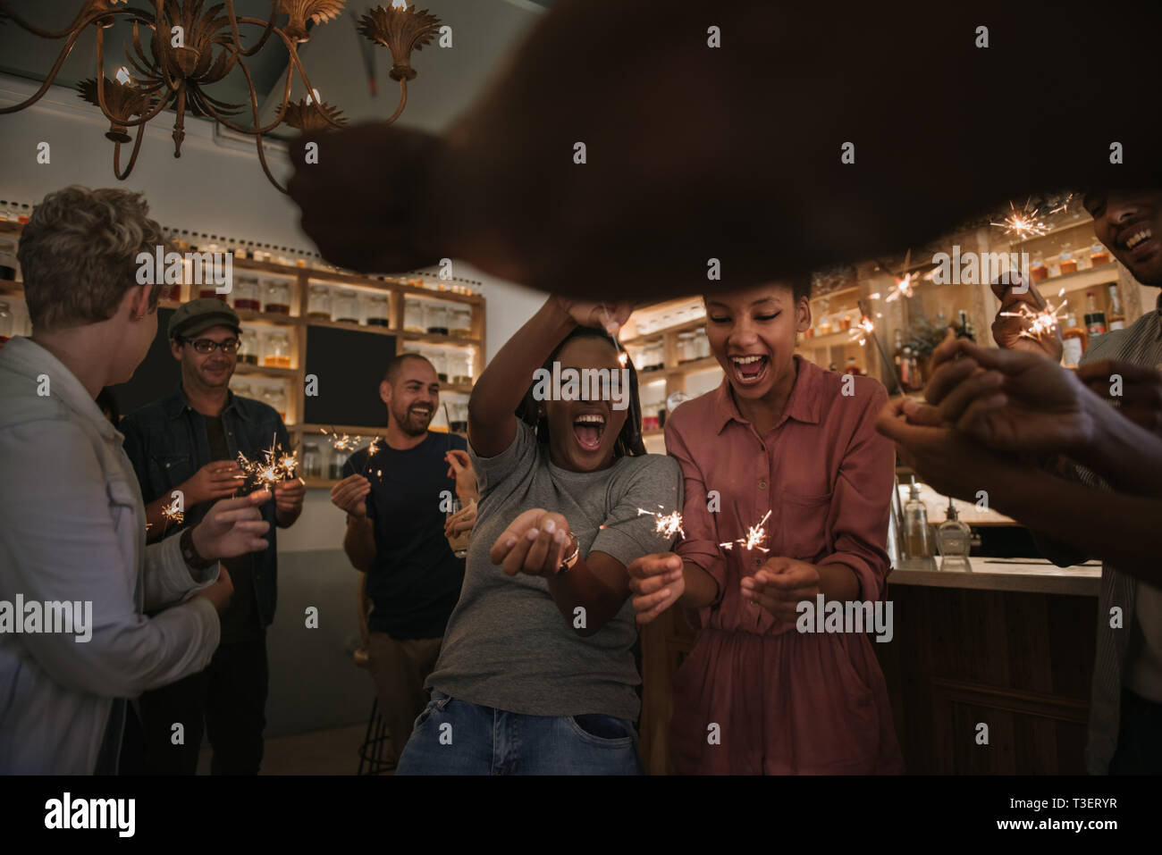 Laughing friends celebrating with sparklers together in a bar Stock Photo