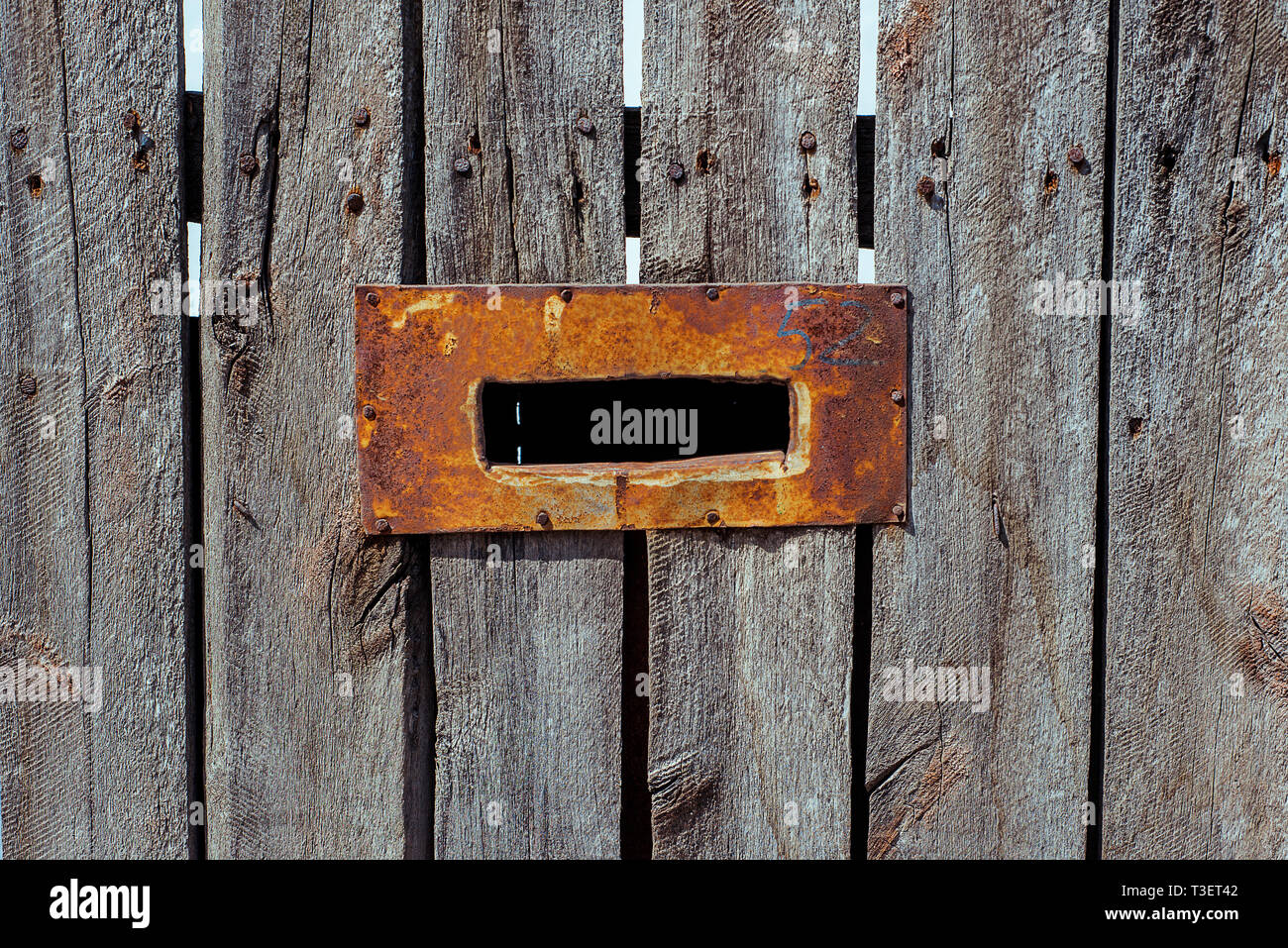 Mail hole with steel rusted frame on the old wooden fence. Stock Photo