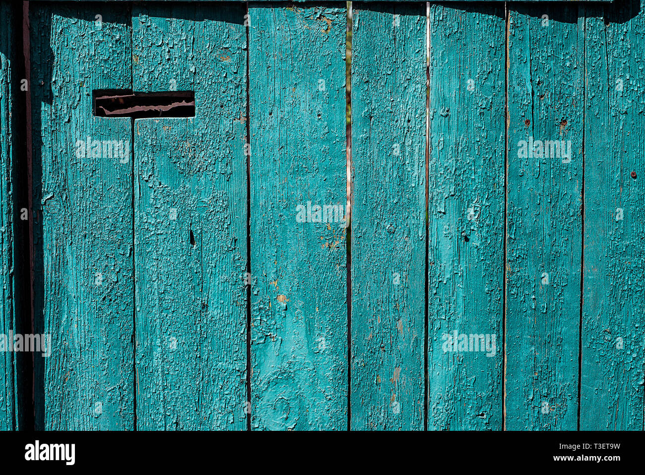 Old blue painted wooden door with mail hole. Horizontal texture of cracked paint on rusty wood Stock Photo