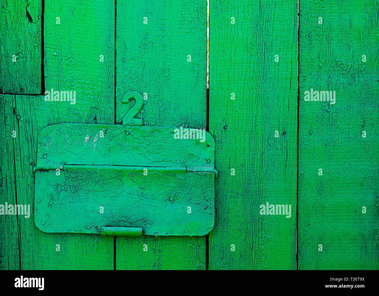 Old green painted wood door with number two and mail hole with green steel cap Stock Photo