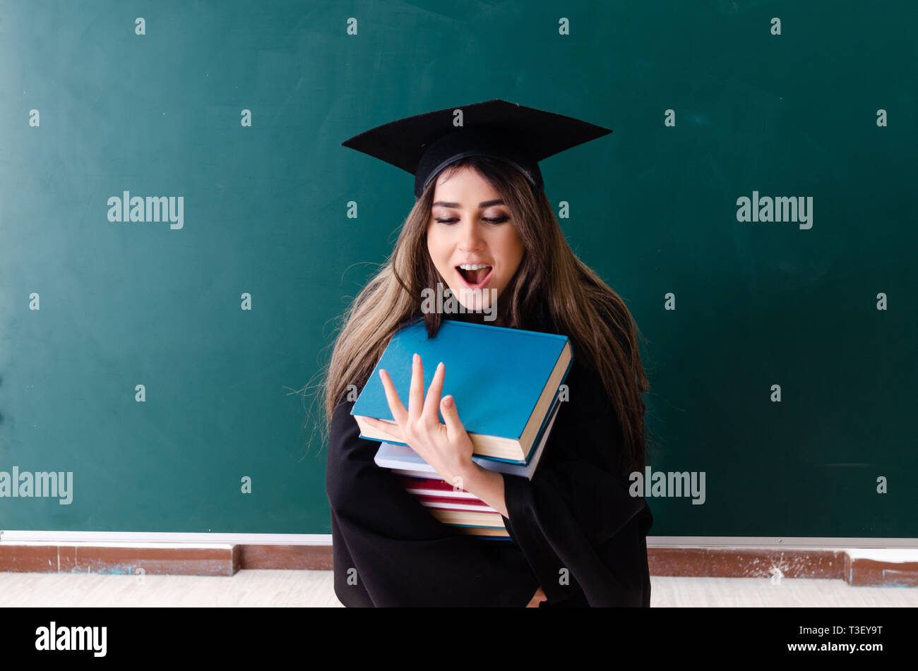Female graduate student in front of green board Stock Photo - Alamy
