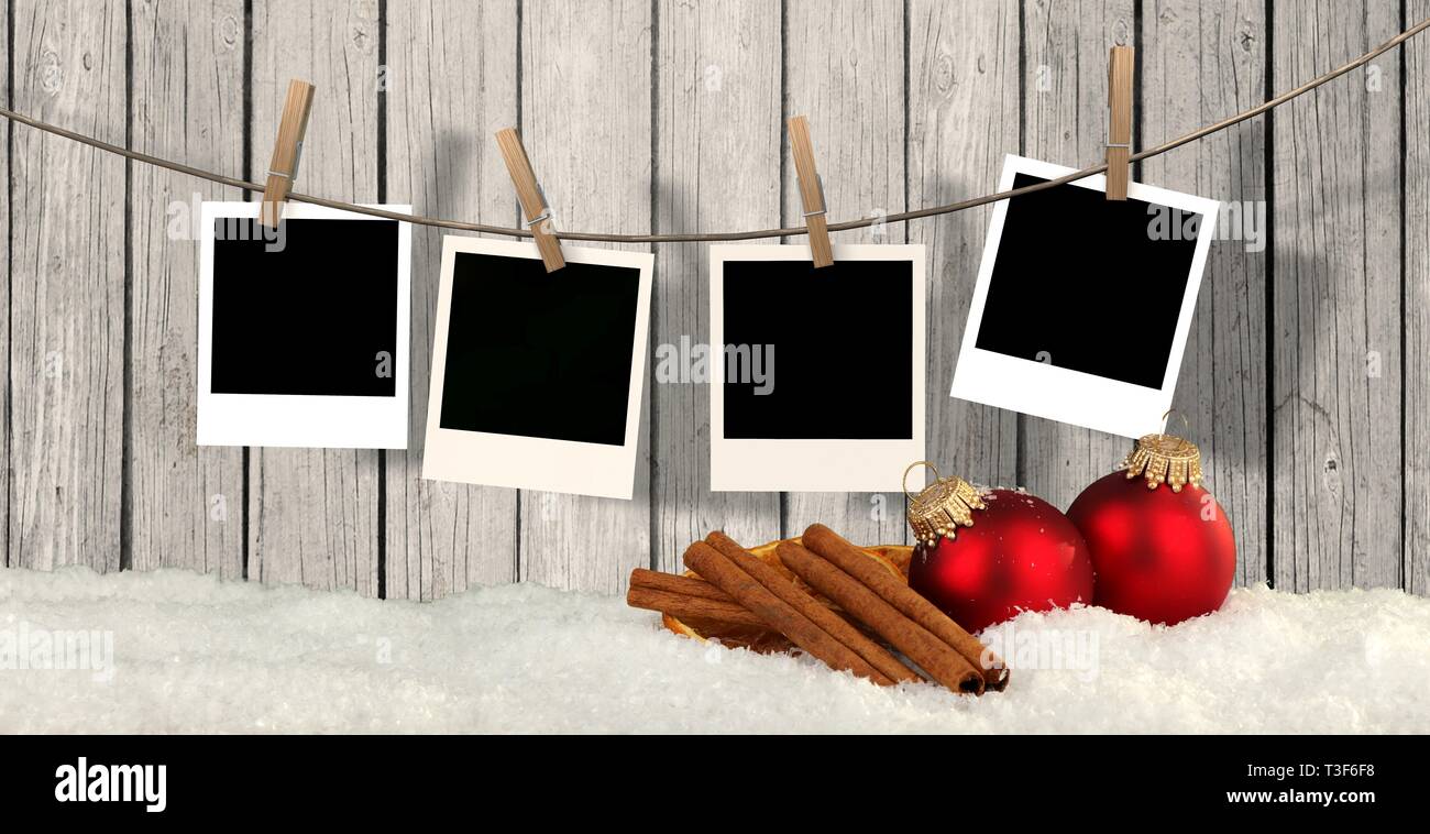 blank instant photos hanging on the clothesline in front of wooden background with snow and christmas balls - christmas background Stock Photo