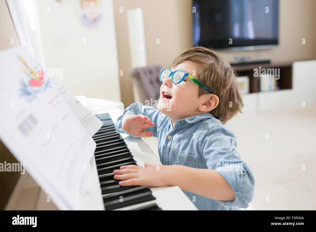 Boy with eyeglasses is playing piano Stock Photo