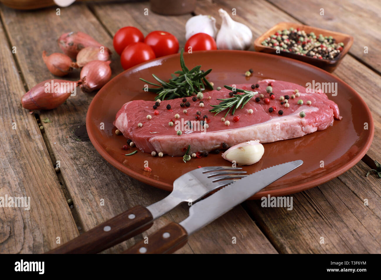 raw rumpsteak beef steak with rosemary, pepper, tomatos and spices on a rustic wooden table Stock Photo