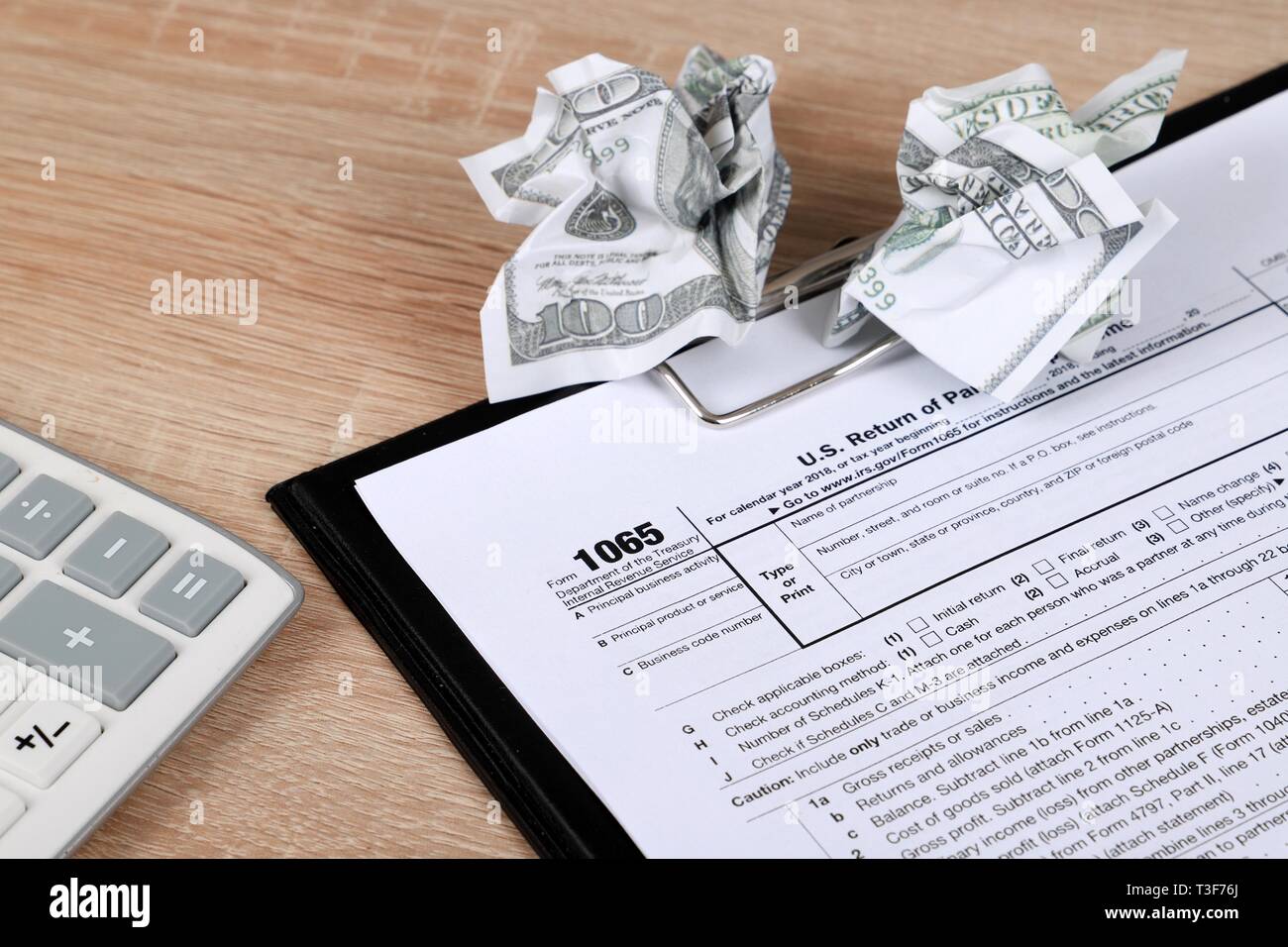 1065 tax form lies near crumpled hundred dollar bills on a Table. US Return for parentship income Stock Photo