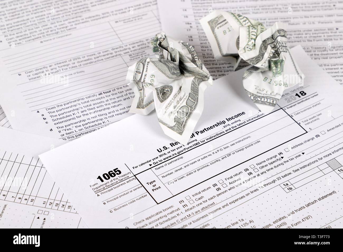 1065 tax form lies near crumpled hundred dollar bills on a Table. US Return for parentship income Stock Photo