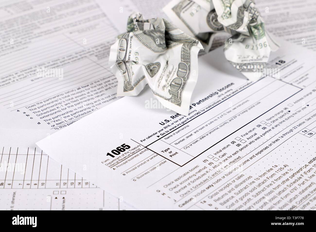 1065 tax form lies near crumpled hundred dollar bills on a Table. US Return for parentship income Stock Photo