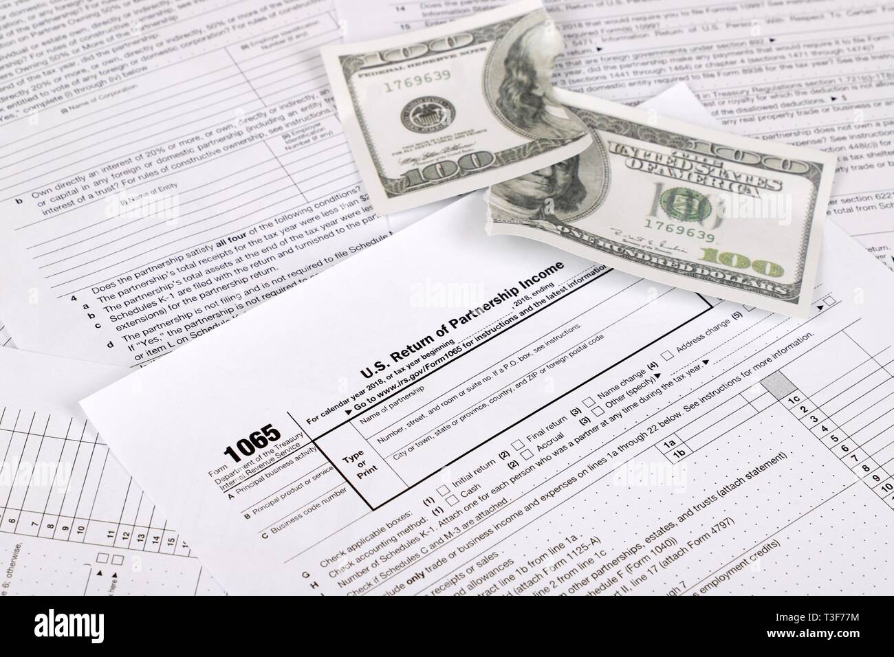 1065 tax form lies near shredded hundred dollar bill on a Table. US Return for parentship income Stock Photo