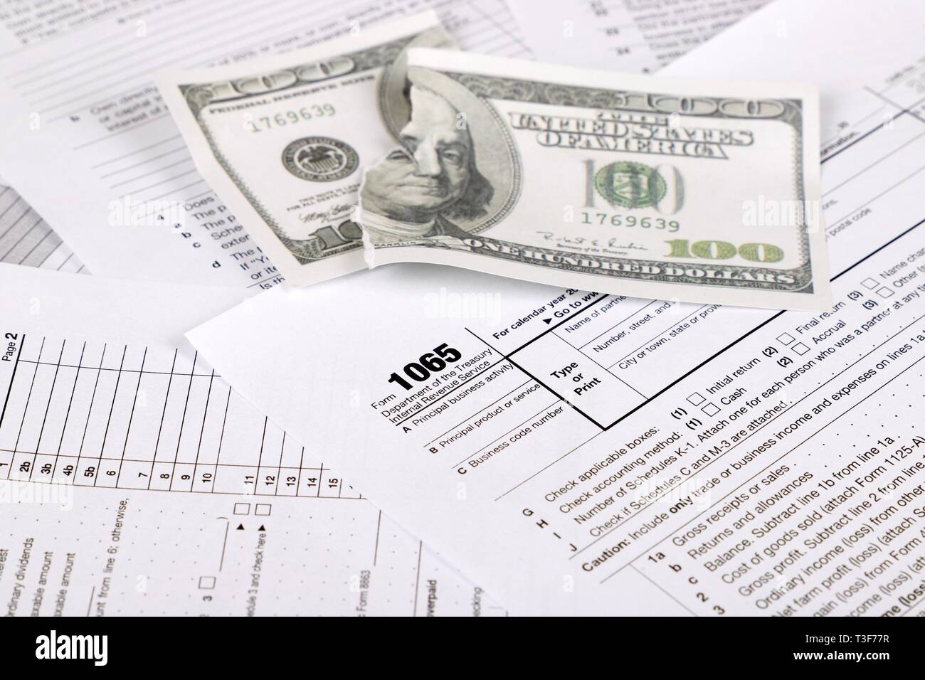 1065 tax form lies near shredded hundred dollar bill on a Table. US Return for parentship income Stock Photo