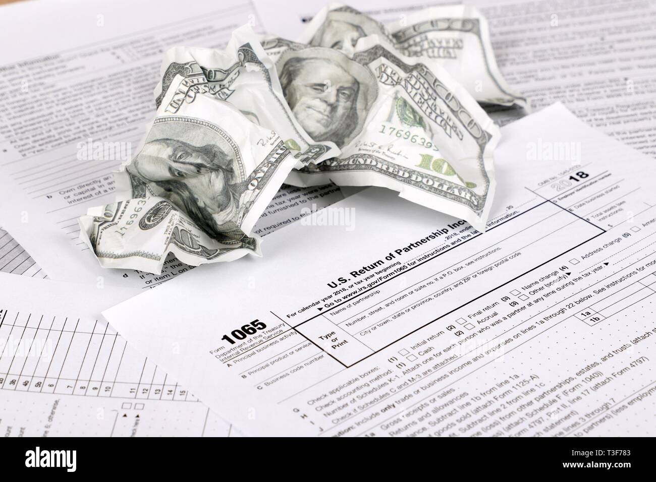 1065 tax form lies near crumpled hundred dollar bills on a Table. US Return for parentship income Stock Photo