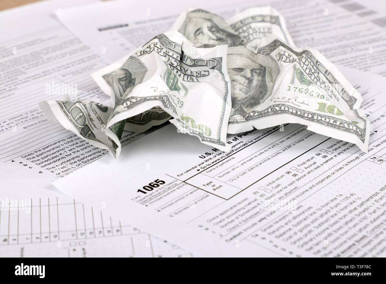 1065 tax form lies near crumpled hundred dollar bills on a Table. US Return for parentship income Stock Photo