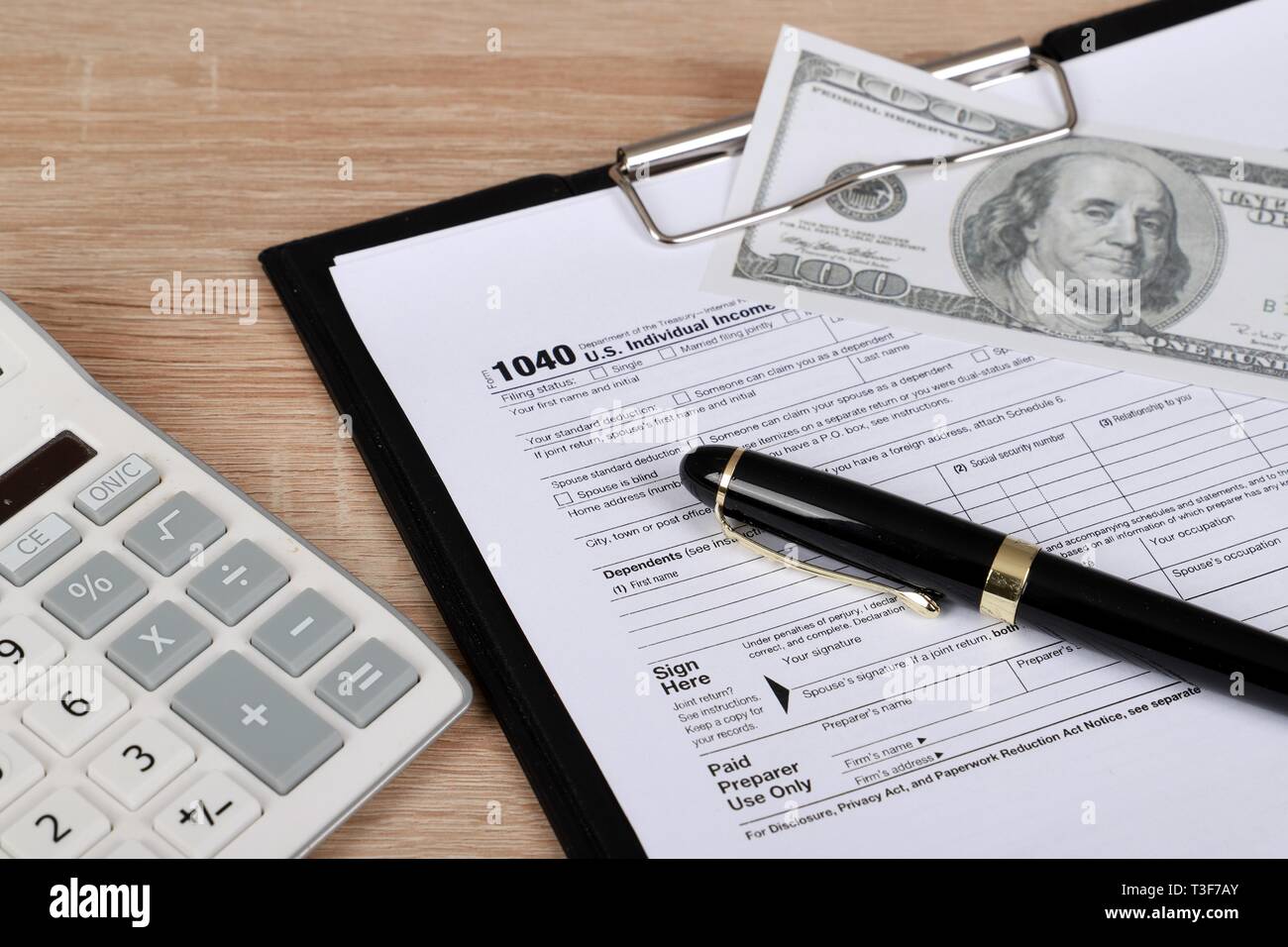 1040 tax form - individual income tax return form 1040 lies near hundred dollar bills and calculator on a Table Stock Photo