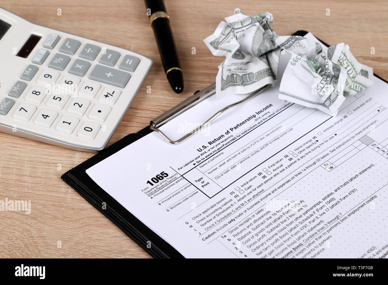 1065 tax form lies near hundred dollar bil and calculator  on a Table. US Return for parentship income Stock Photo