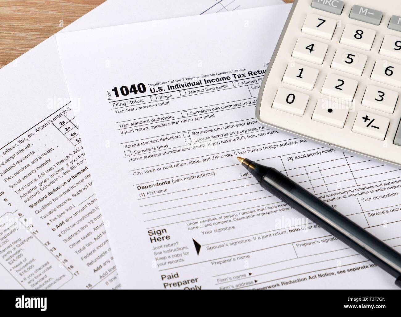 1040 tax form - individual income tax return form 1040 lies near hundred dollar bills and calculator on a Table Stock Photo