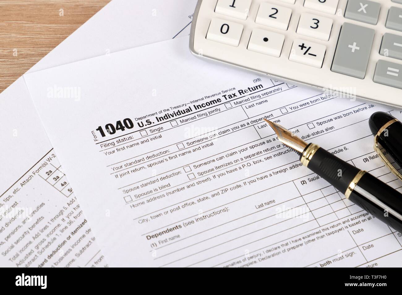 1040 tax form - individual income tax return form 1040 lies near hundred dollar bills and calculator on a Table Stock Photo