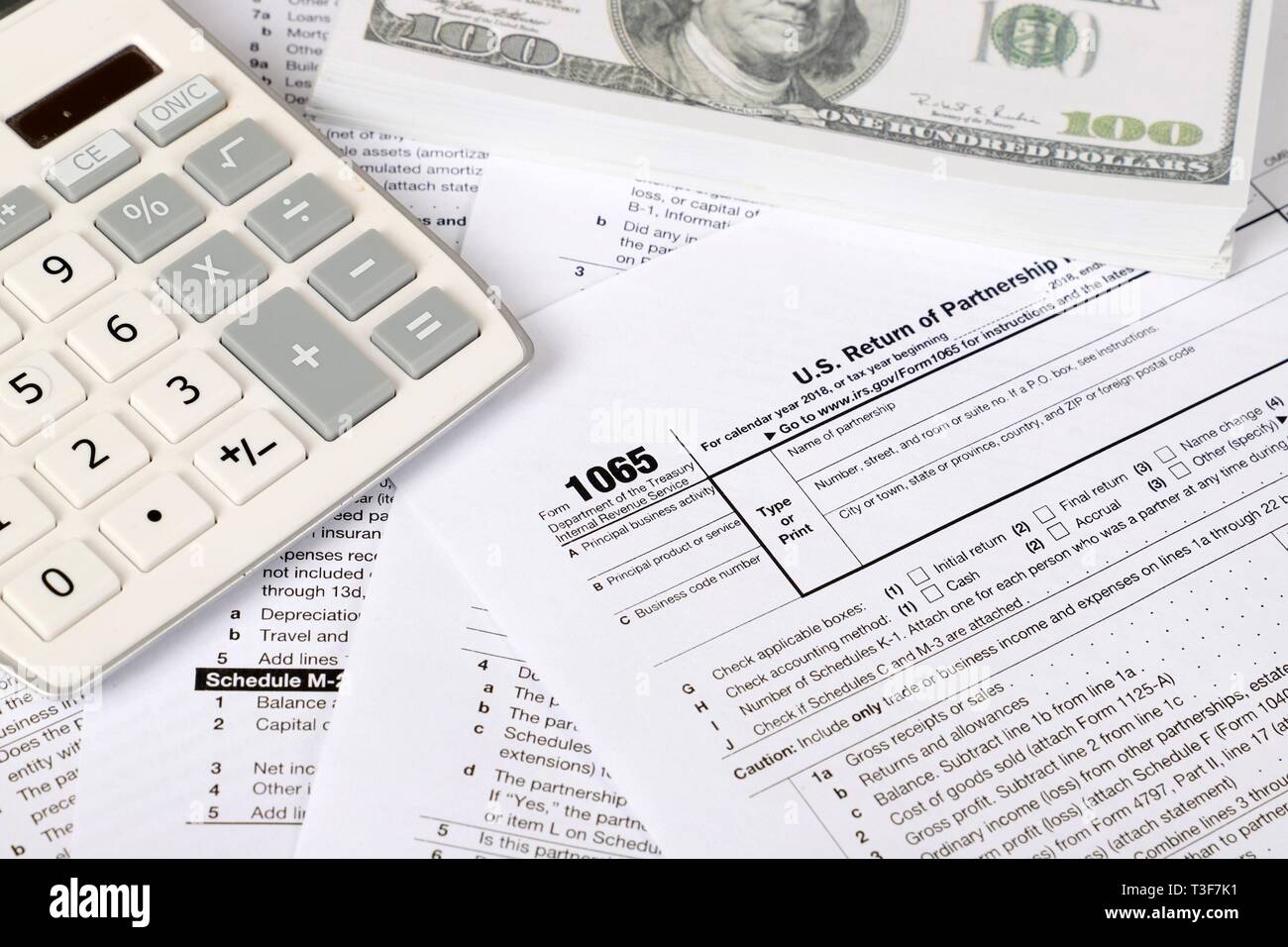 1065 tax form lies near hundred dollar bil and calculator  on a Table. US Return for parentship income Stock Photo