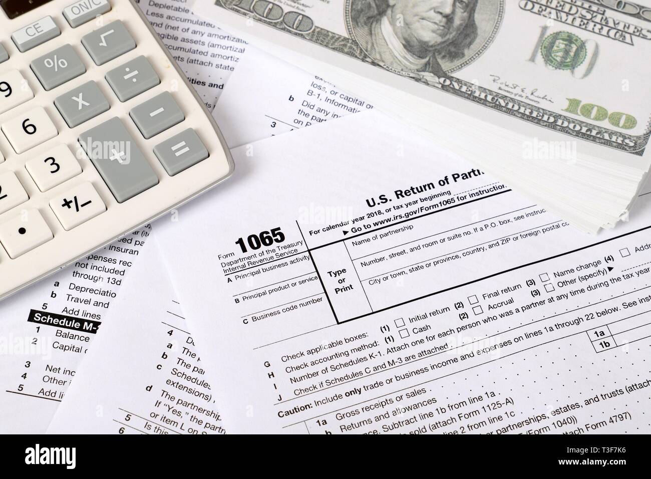 1065 tax form lies near hundred dollar bil and calculator  on a Table. US Return for parentship income Stock Photo