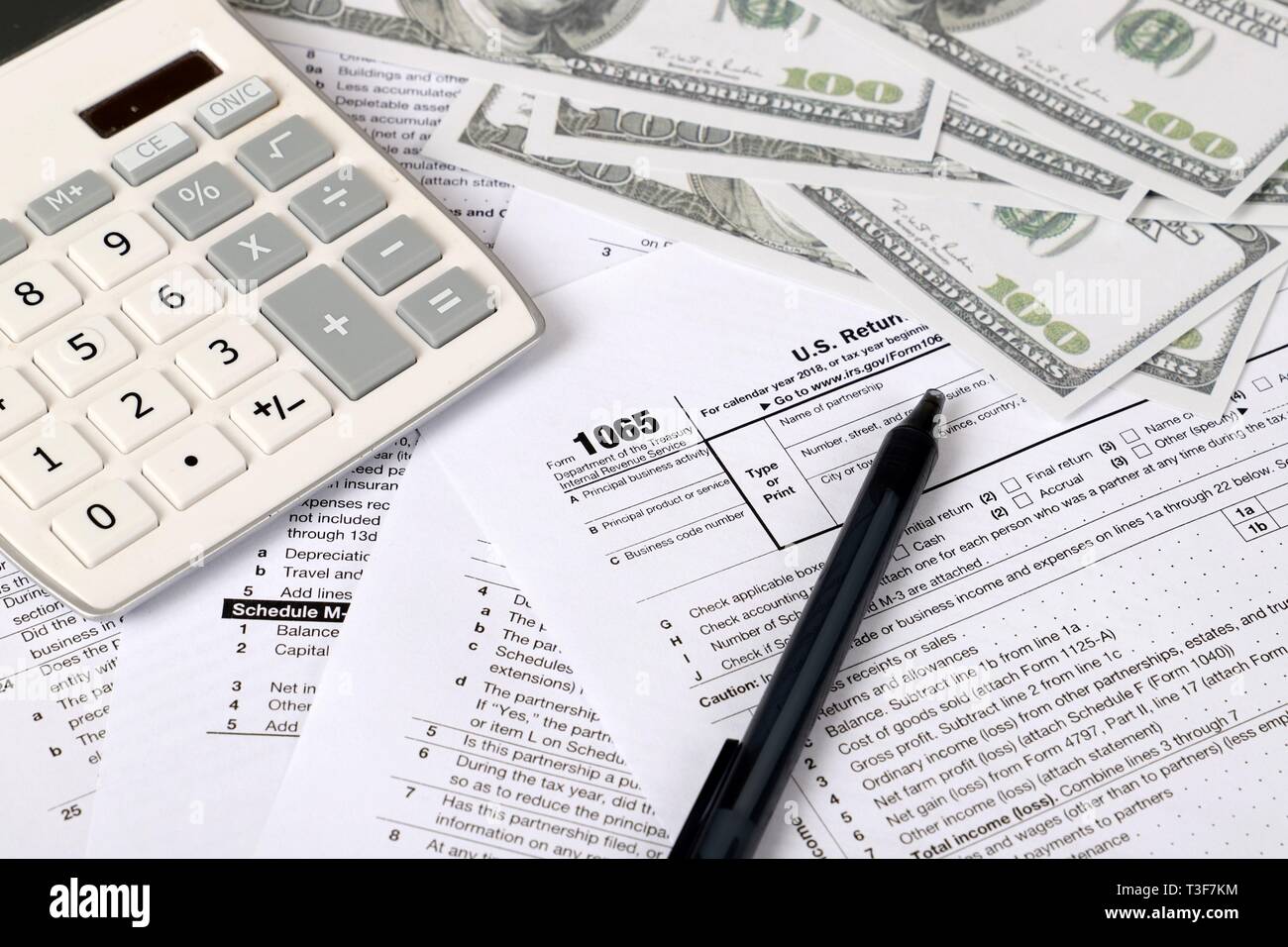 1065 tax form lies near hundred dollar bil and calculator  on a Table. US Return for parentship income Stock Photo