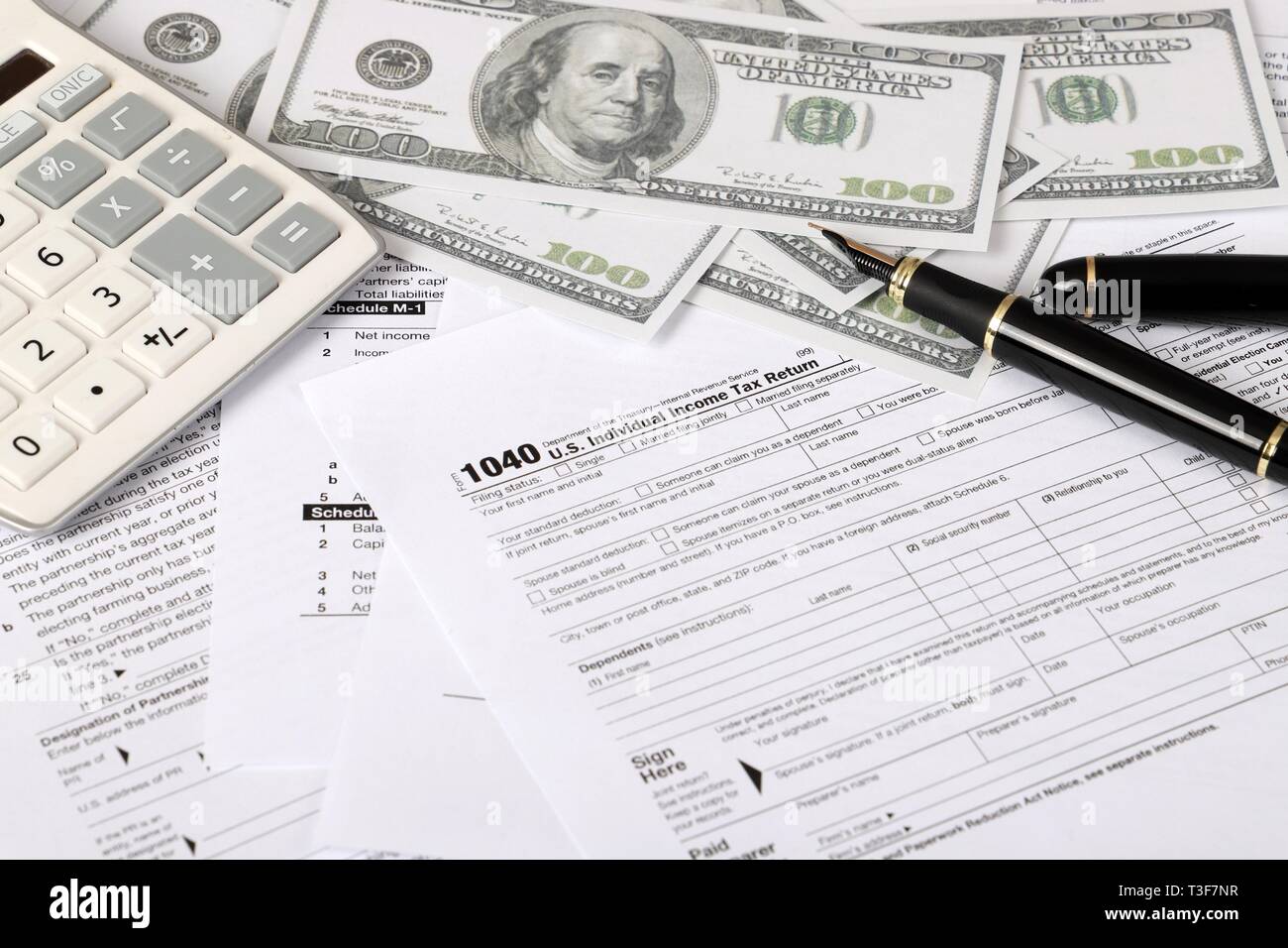 1040 tax form - individual income tax return form 1040 lies near hundred dollar bills and calculator on a Table Stock Photo