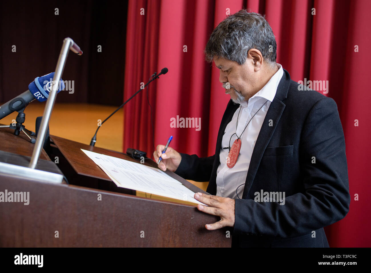 09 April 2019, Bavaria, München: Gudju Gudju Fourmile, elder of the Gimuy Walubara Yidindji and head of the community, signs the handover documents at the ceremony for the return of the mortal remains of an Australian indigenous in the Museum Five Continents. Photo: Matthias Balk/dpa Stock Photo