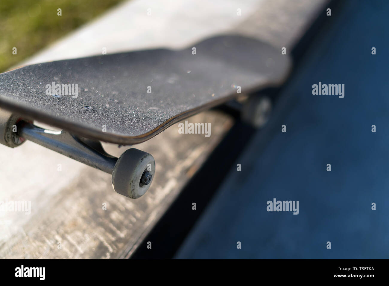 Professional skateboard laying on concrete ledge at skate park