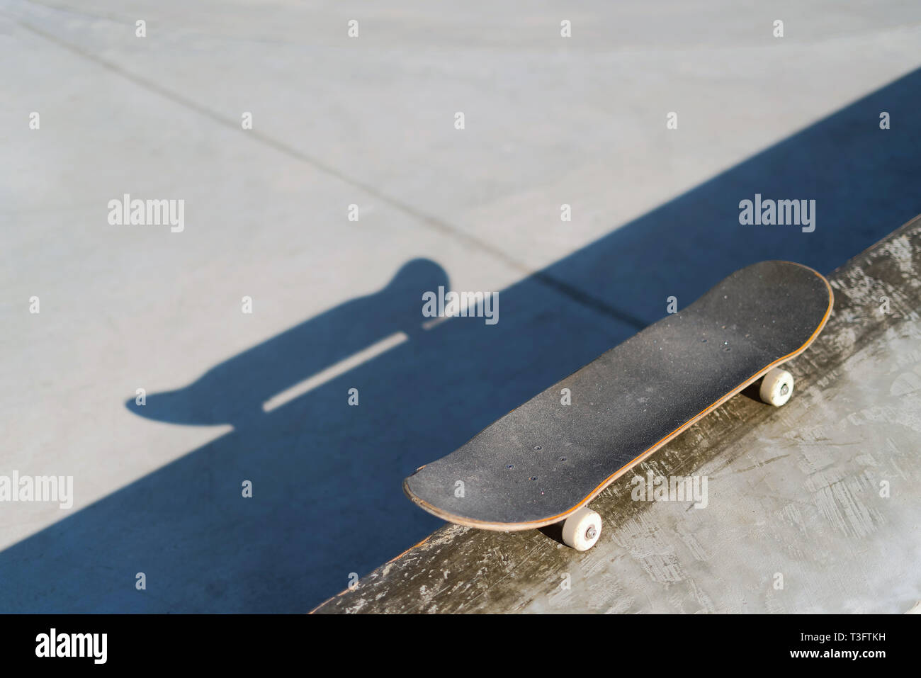 Professional skateboard laying on concrete ledge at skate park