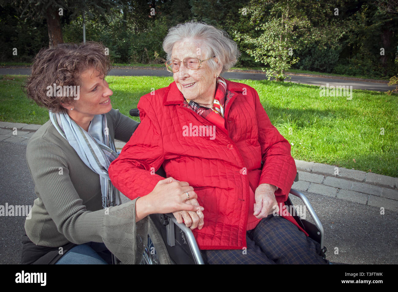 Young woman holding hand of senior woman sitting in wheelchair Stock Photo