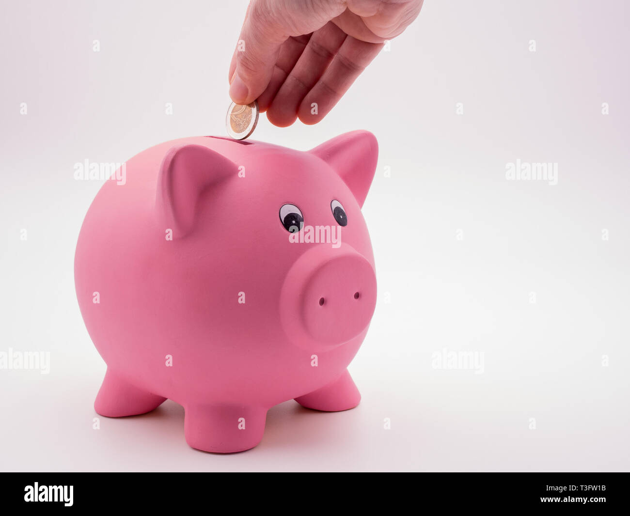 Hand putting euro going into piggy bank Stock Photo - Alamy