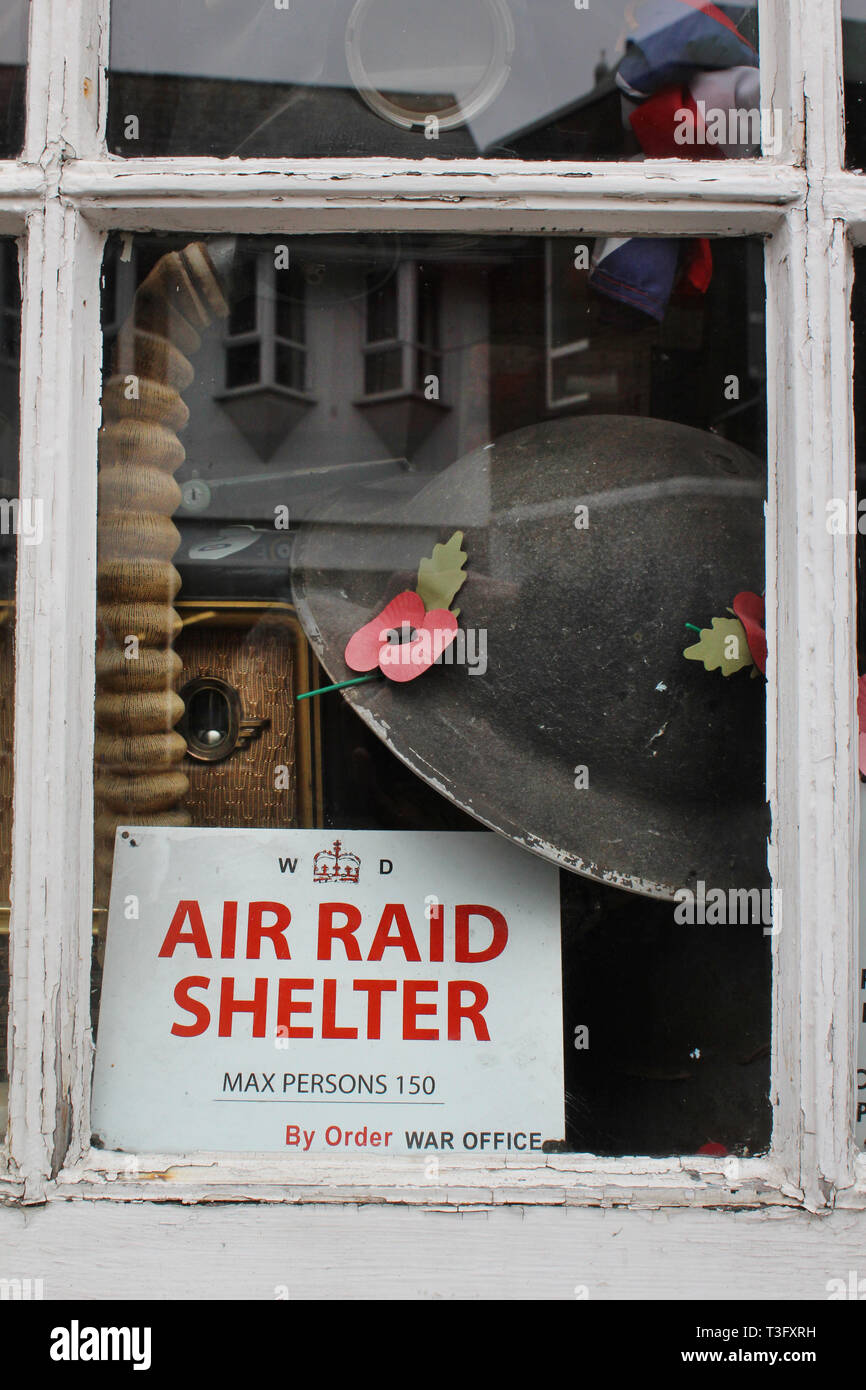 Pawn shop window with air shelter sign, hat among other second hand objects, Littlehampton, West Sussex, England, UK Stock Photo