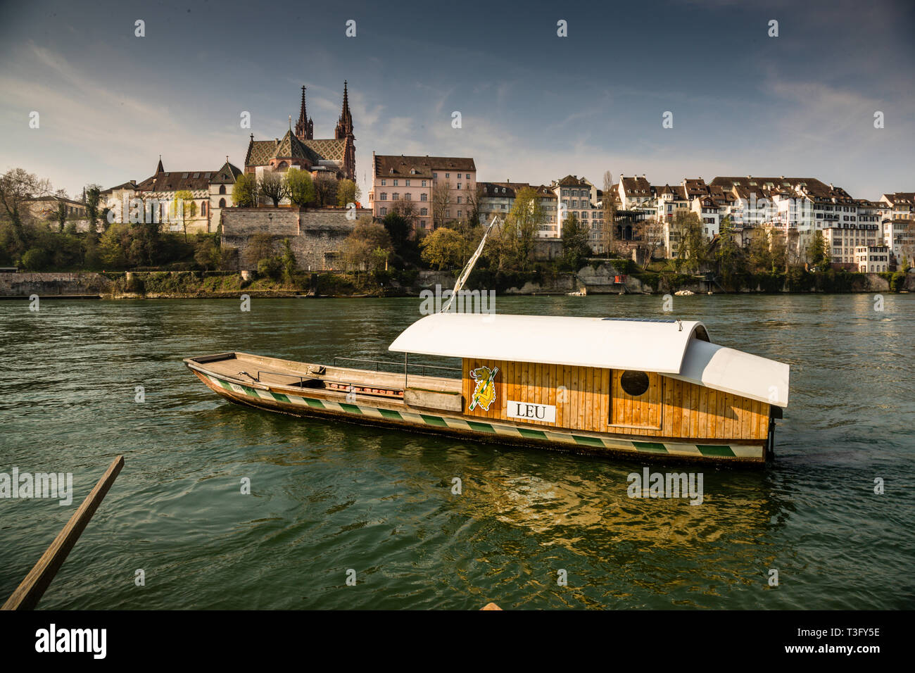 The Basel Rhine ferry "Leu" at the cathedral. In the midday hours, people like to cross to the other side for lunch, which is then in the sun. A crossing costs 1.60 francs or euros. Leu Ferry at the Cathedral in Basel, Switzerland Stock Photo