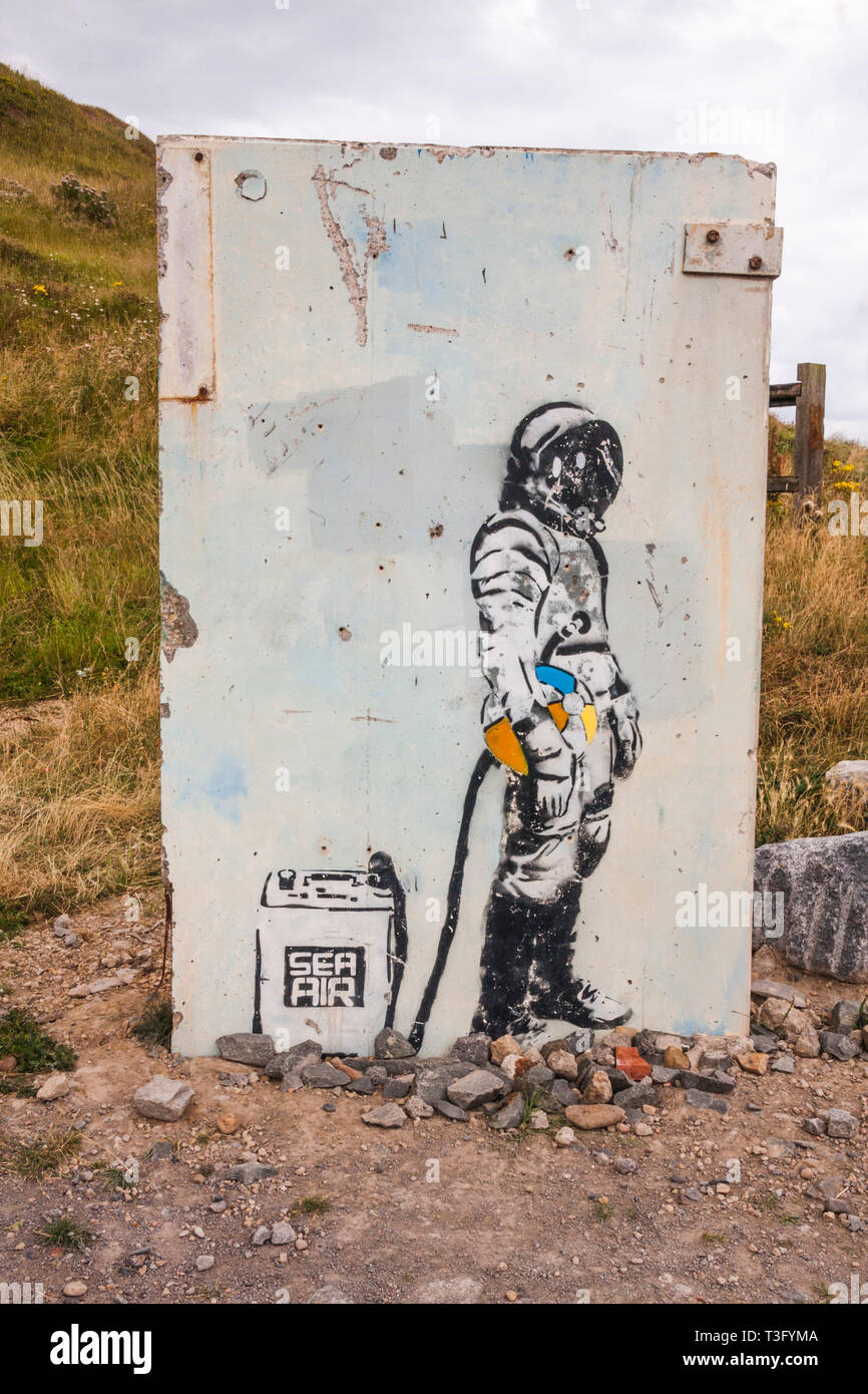 Wall art picture of deep sea diver holding a beach ball and hooked up to 'sea air' container at Skinningrove,North Yorkshire Stock Photo