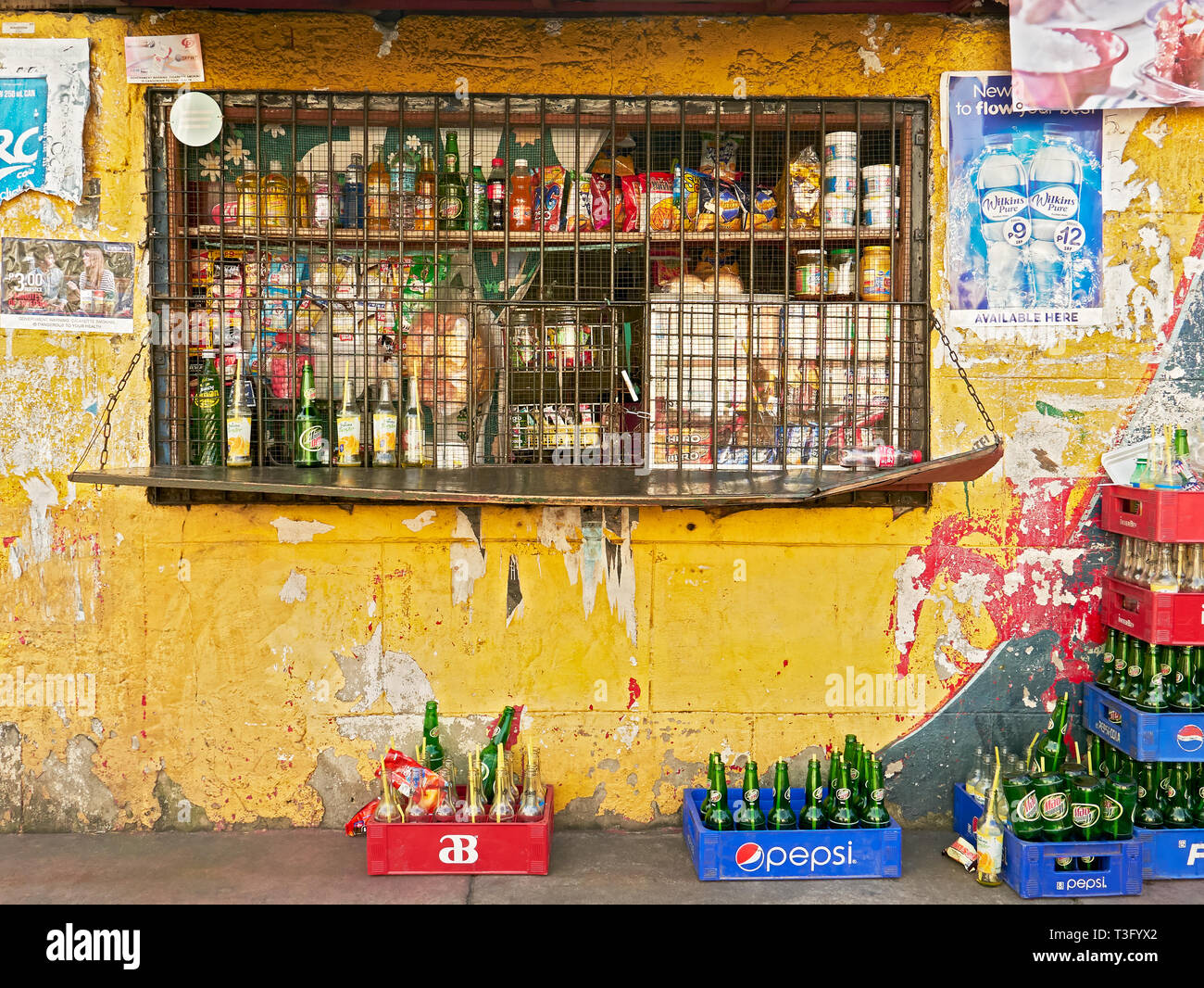 Manila, Philippines: Grilled window of a crowded neighborhood sari-sari store with trash and empty soft drink bottles and cages Stock Photo