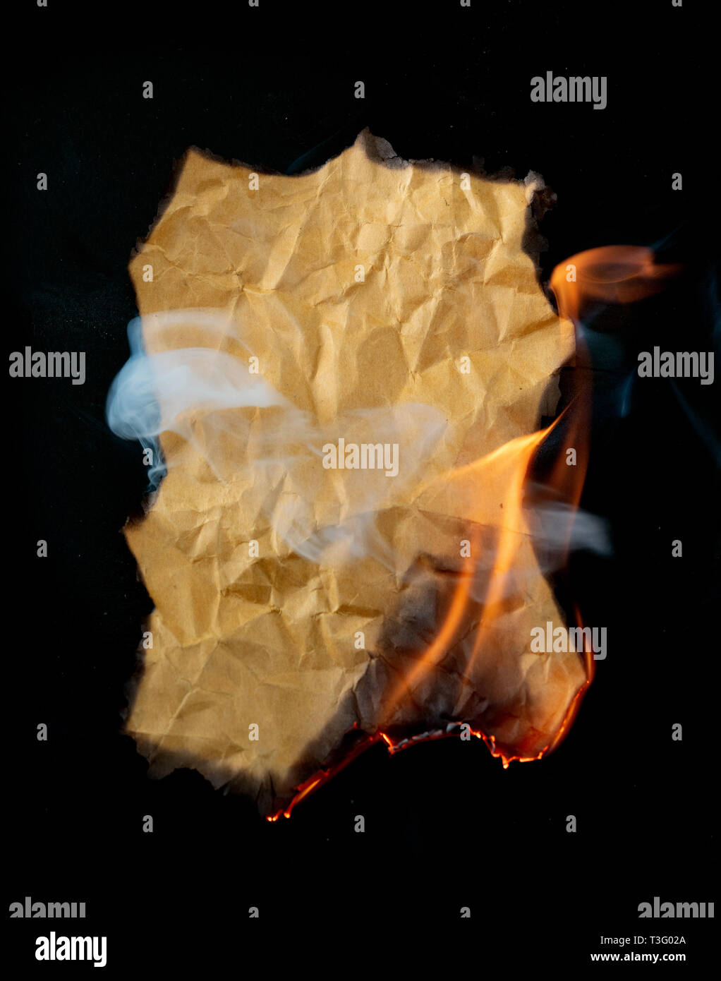 burning piece of crumpled paper on black background Stock Photo