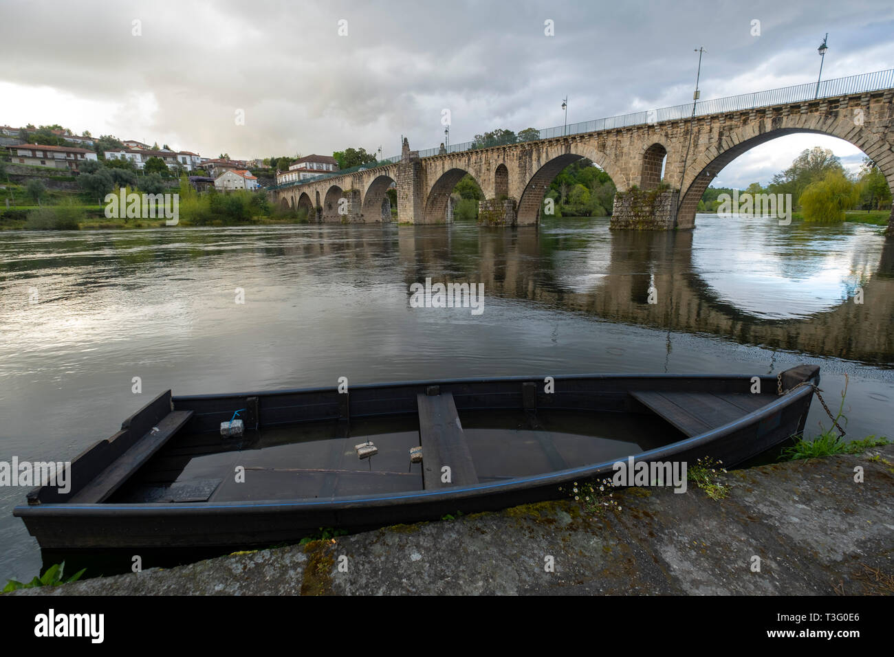 Wooden boat next to the medieval stone bridge over the Lima river in Ponte da Barca, Minho, Portugal, Europe Stock Photo