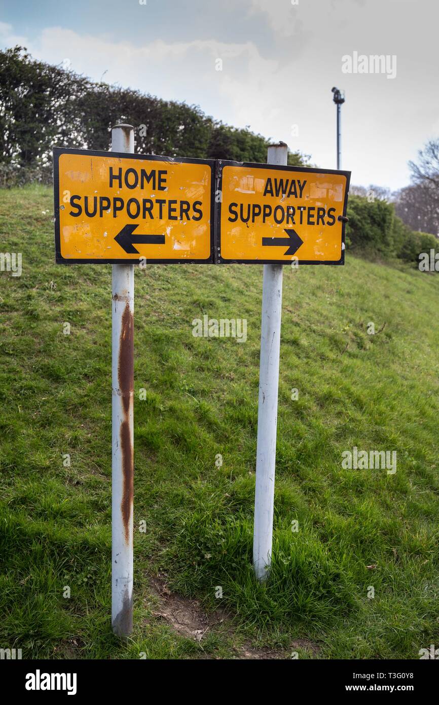 Sign on approach to English football ground indicating direction away and home fans should take Stock Photo