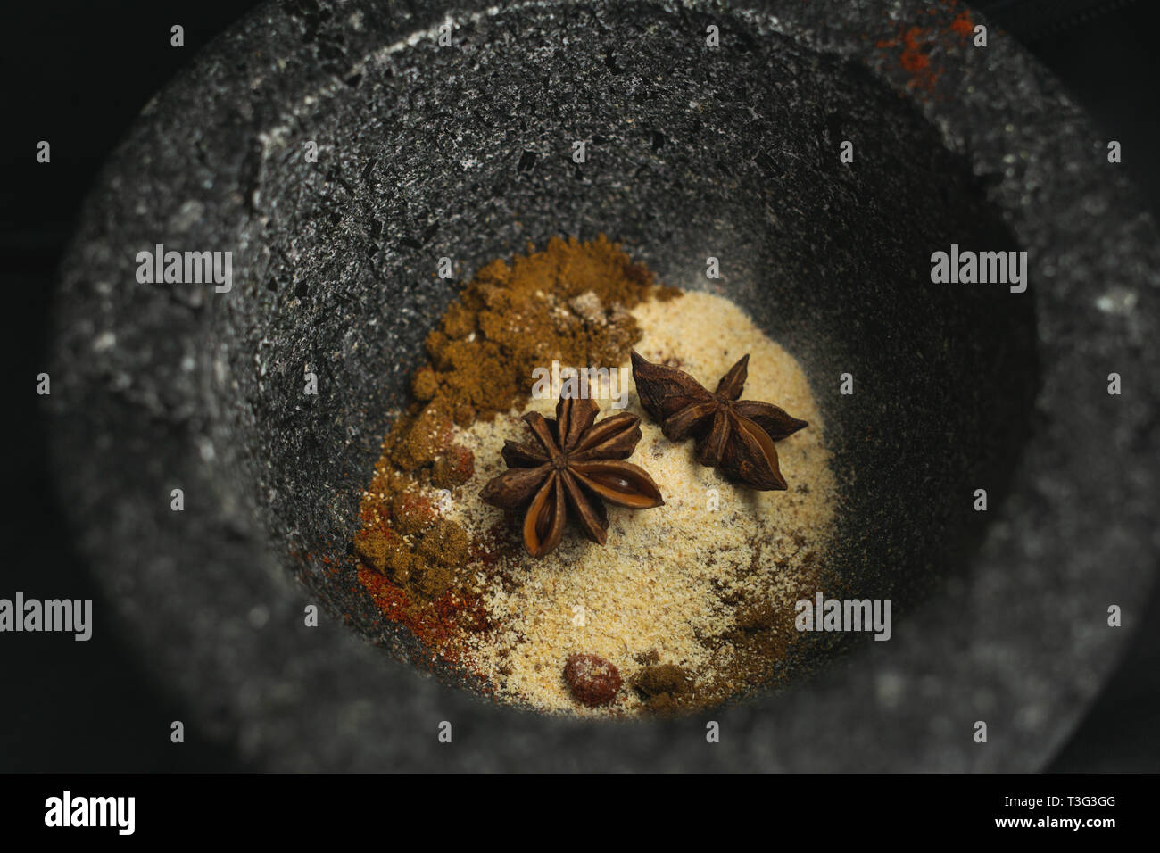A mixture of spices in a stone pestle and mortar ready to be ground Stock Photo