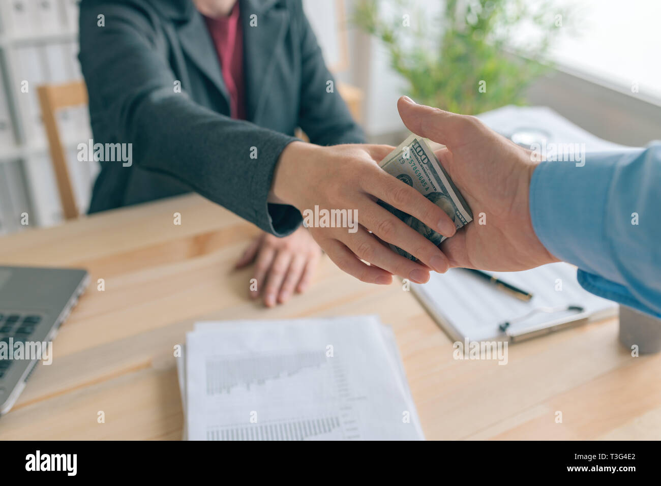 Hush money and corruption in business concept, close up of male hand giving hundred US dollar pbill to female business person Stock Photo