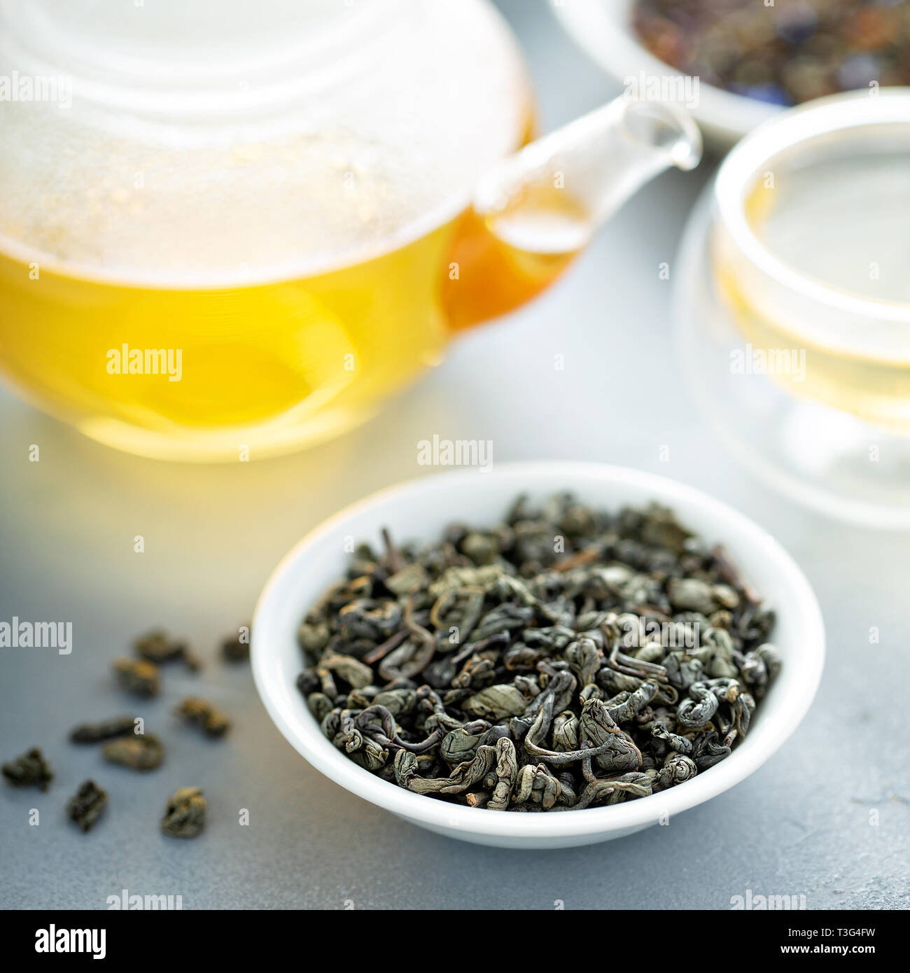 Green loose leaf tea and a teapot Stock Photo