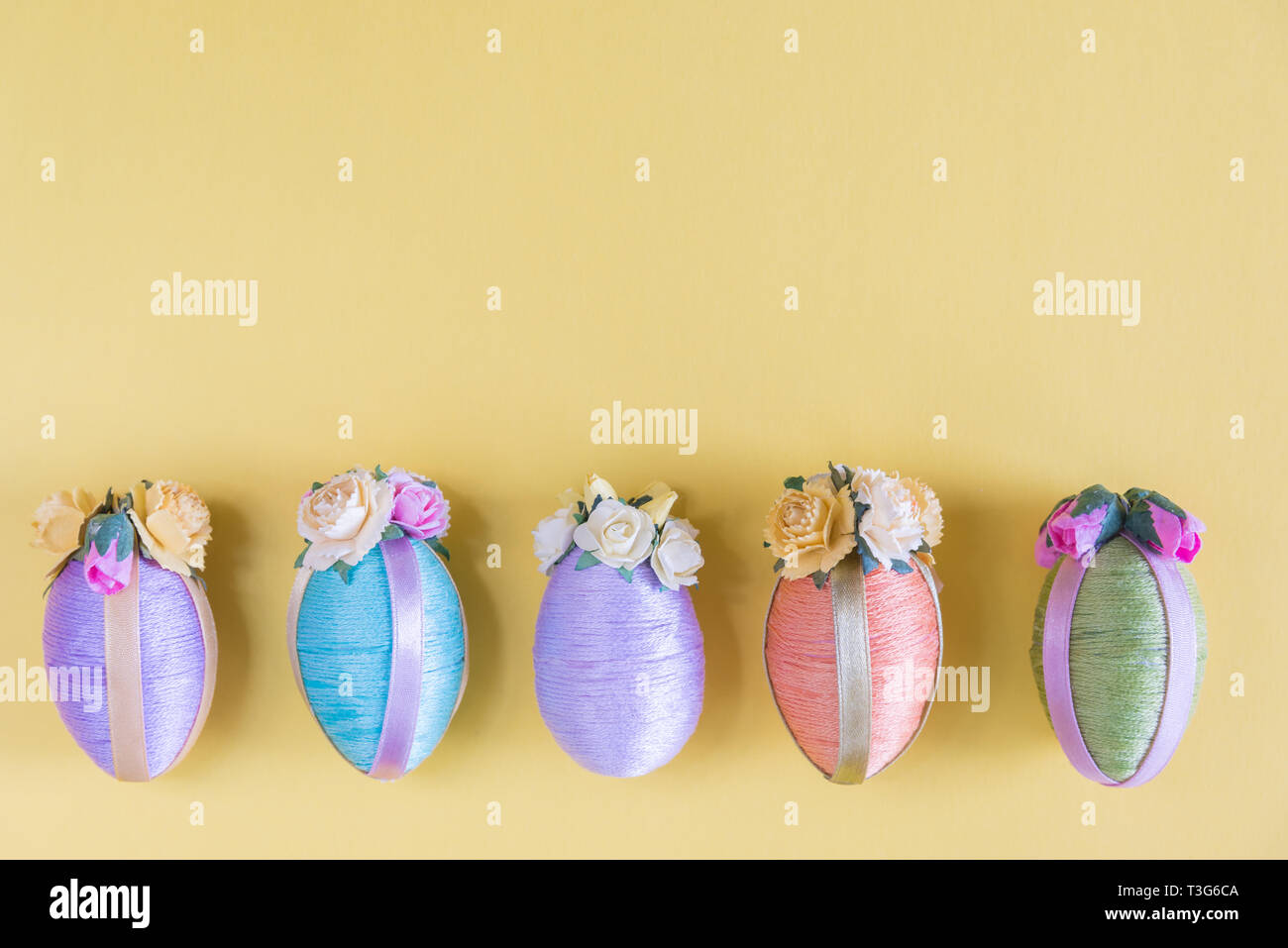 Multi-color vintage style Easter eggs in row on solid yellow background Stock Photo