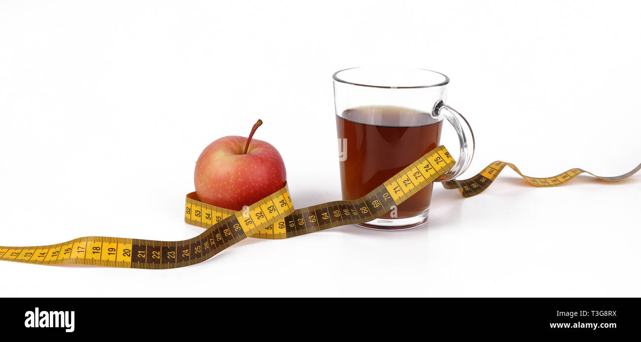 Slimming with tea and fruits, a cup with tea and a measuring tape and a delicious red apple isolated on white background Stock Photo