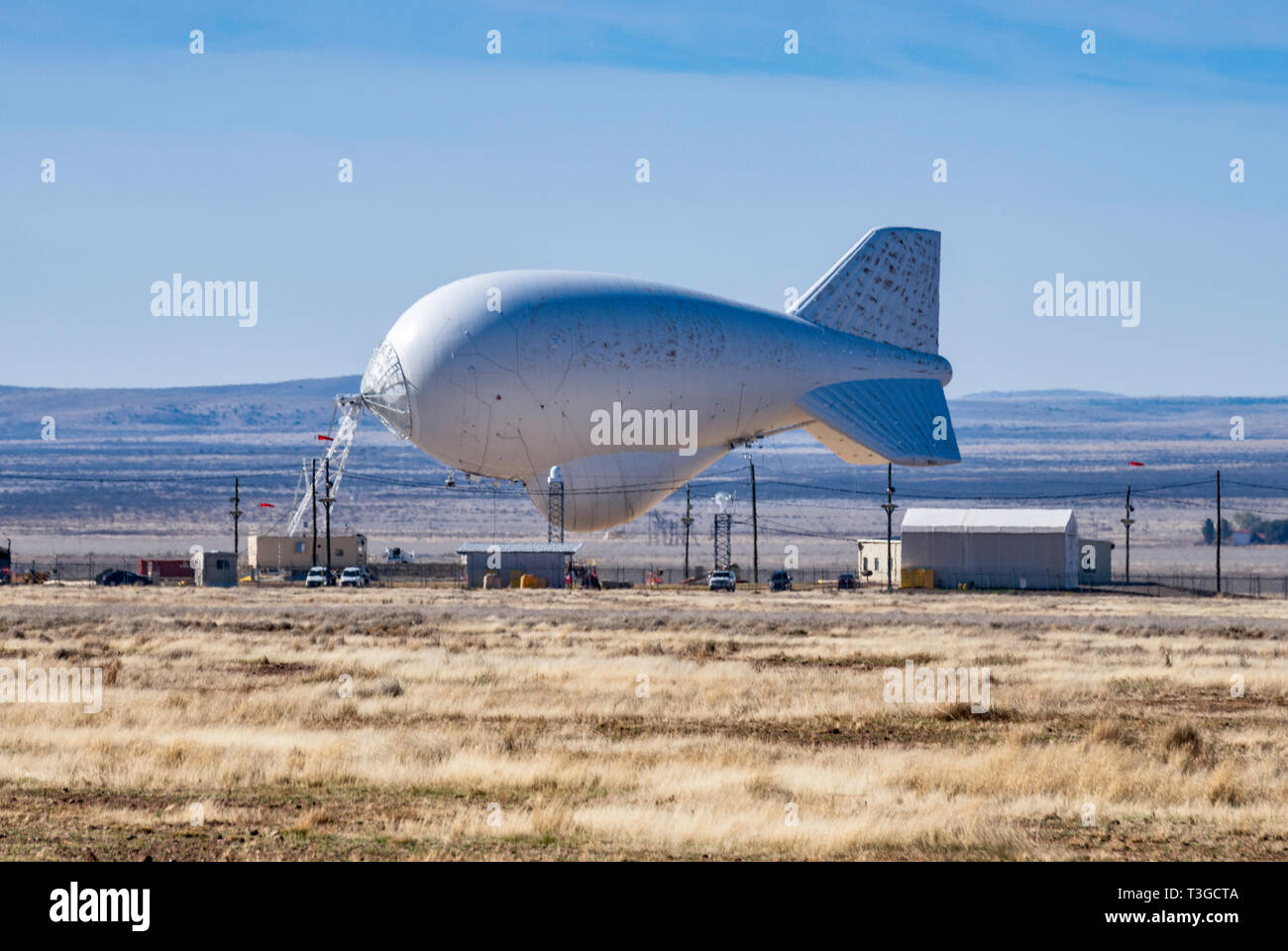 Aerostat surveillance blimp with downward-looking radar for drug smugglers aircraft detection, low on ground due to strong winds, near Marfa, Texas Stock Photo