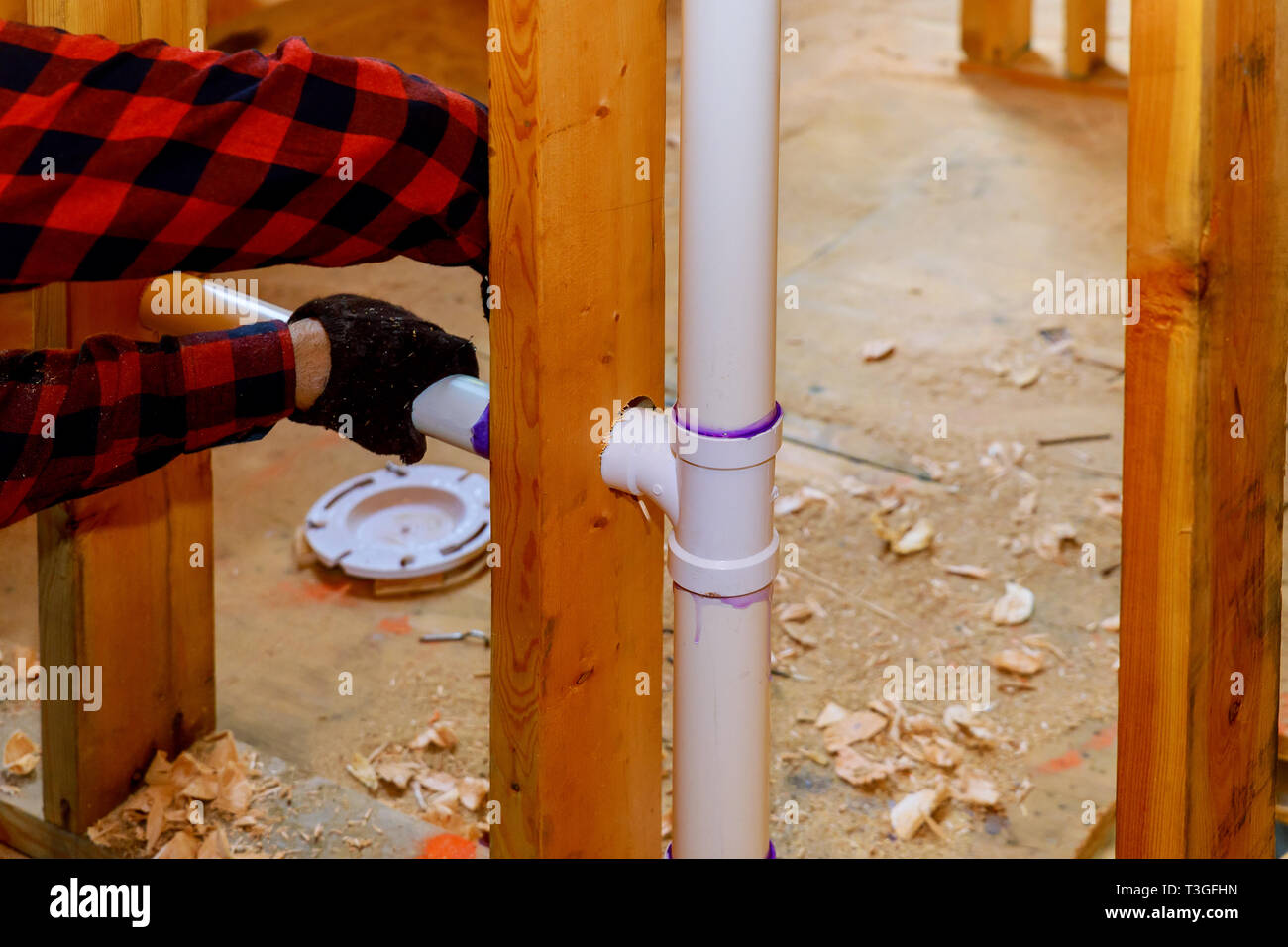 Close up on t joint and pipes for home sewage system, in wood wall
