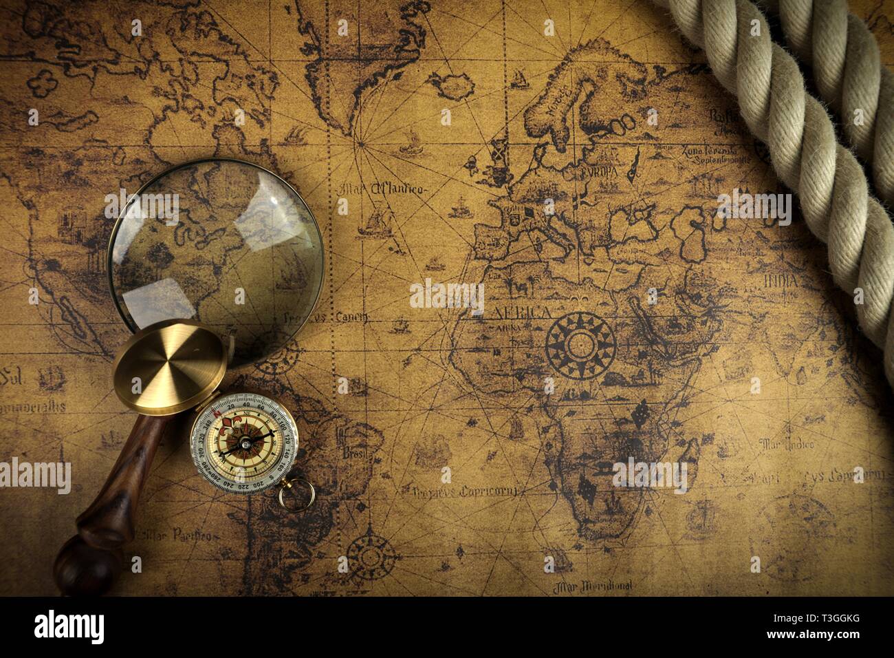 Vintage Compass and magnifying glass lies on an ancient world map - adventure stories background Stock Photo