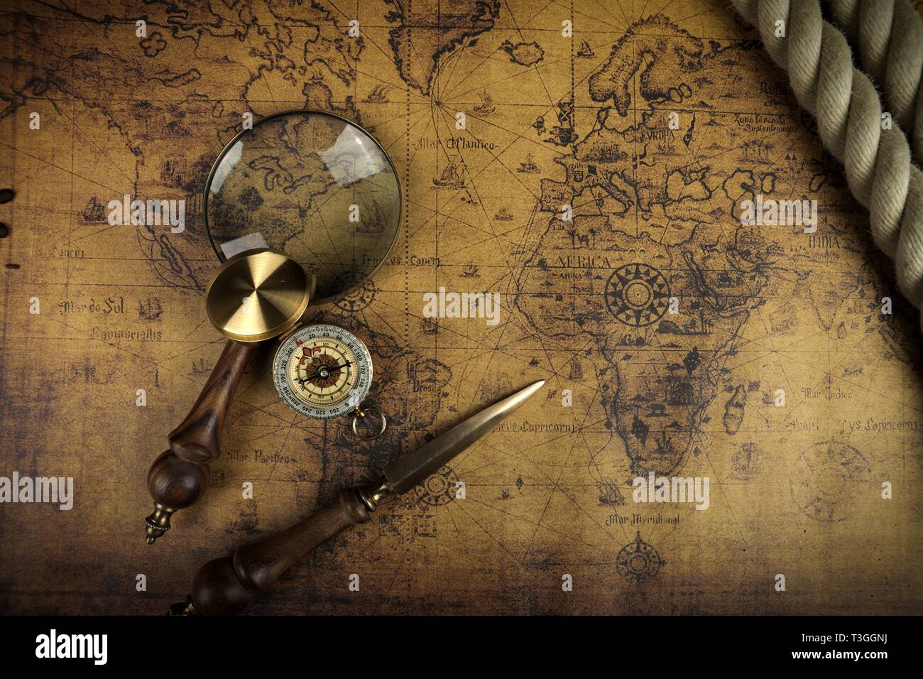 Vintage Compass and magnifying glass lies on an ancient world map - adventure stories background Stock Photo