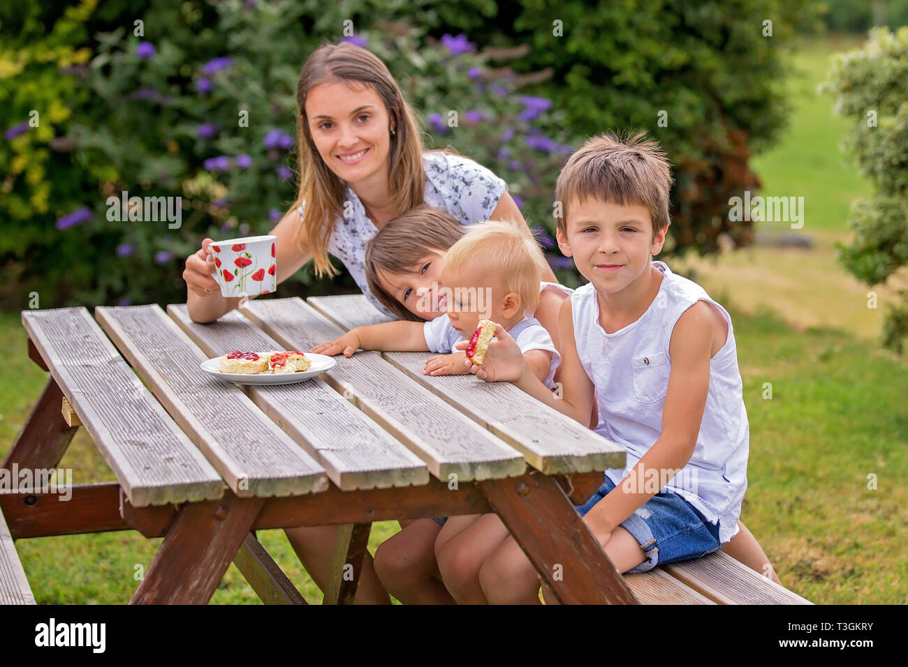 Mother and three children, having afternoon tea in the backyard of